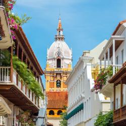 Ruelle coloniale aux balcons fleuris donnant sur le clocher de la cathédrale de Carthagène des Indes en Colombie.