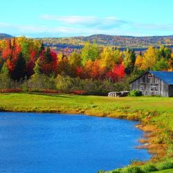 Paysage d'été indien avec forêt d'érables aux couleurs d'automne et grange au bord d'un lac au Québec, Canada