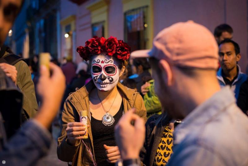 Femme maquillee en Catrina avec couronne de fleurs lors d un defile de rue a Oaxaca