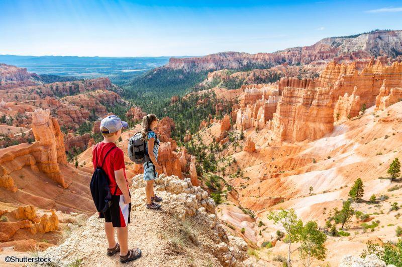 Circuit Ouest Américain en famille : randonnée et panorama spectaculaire à Bryce Canyon Une famille contemplant les formations rocheuses ocre et les cheminées de fée du parc national de Bryce Canyon depuis un point de vue panoramique.