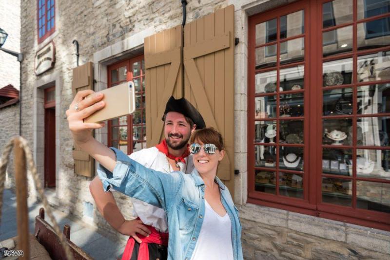 Visiteurs prenant un selfie aux côtés d'un guide en costume d'époque lors d'une visite guidée de Québec au Canada