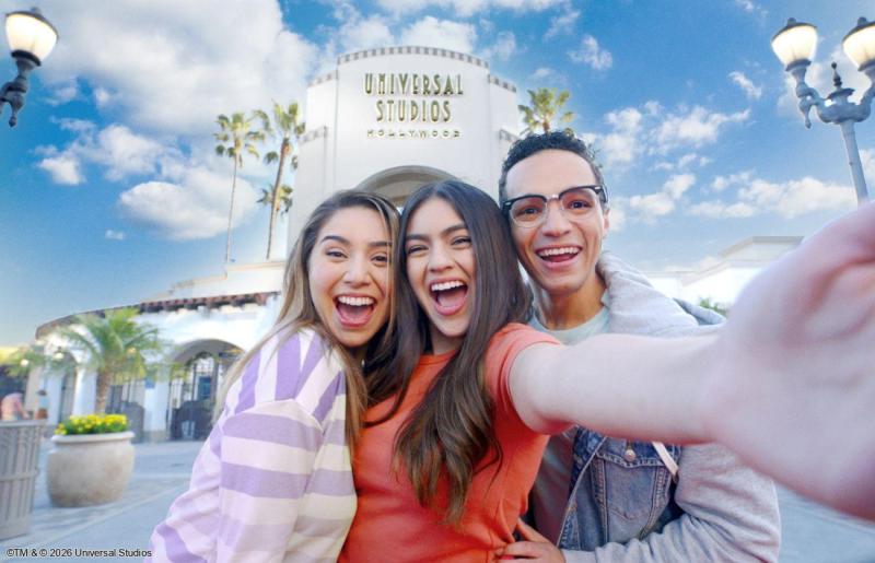 Circuit Ouest Américain en famille : immersion dans les coulisses du cinéma à Universal Studios Hollywood Trois jeunes visiteurs tout souriants se prenant en selfie devant l'entrée emblématique des studios Universal Studios Hollywood à Los Angeles.