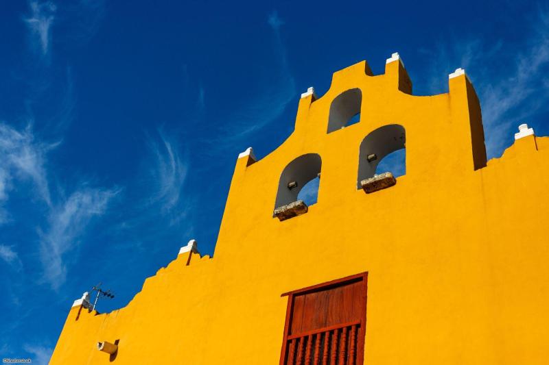 Façade coloniale jaune vif et clocher pignon sous un ciel bleu à Campeche au Mexique