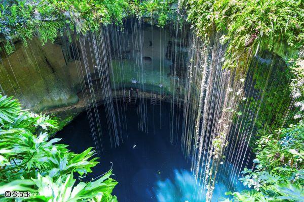 Vue plongeante sur le cenote Ik Kil bordé de lianes et de végétation au Yucatan au Mexique